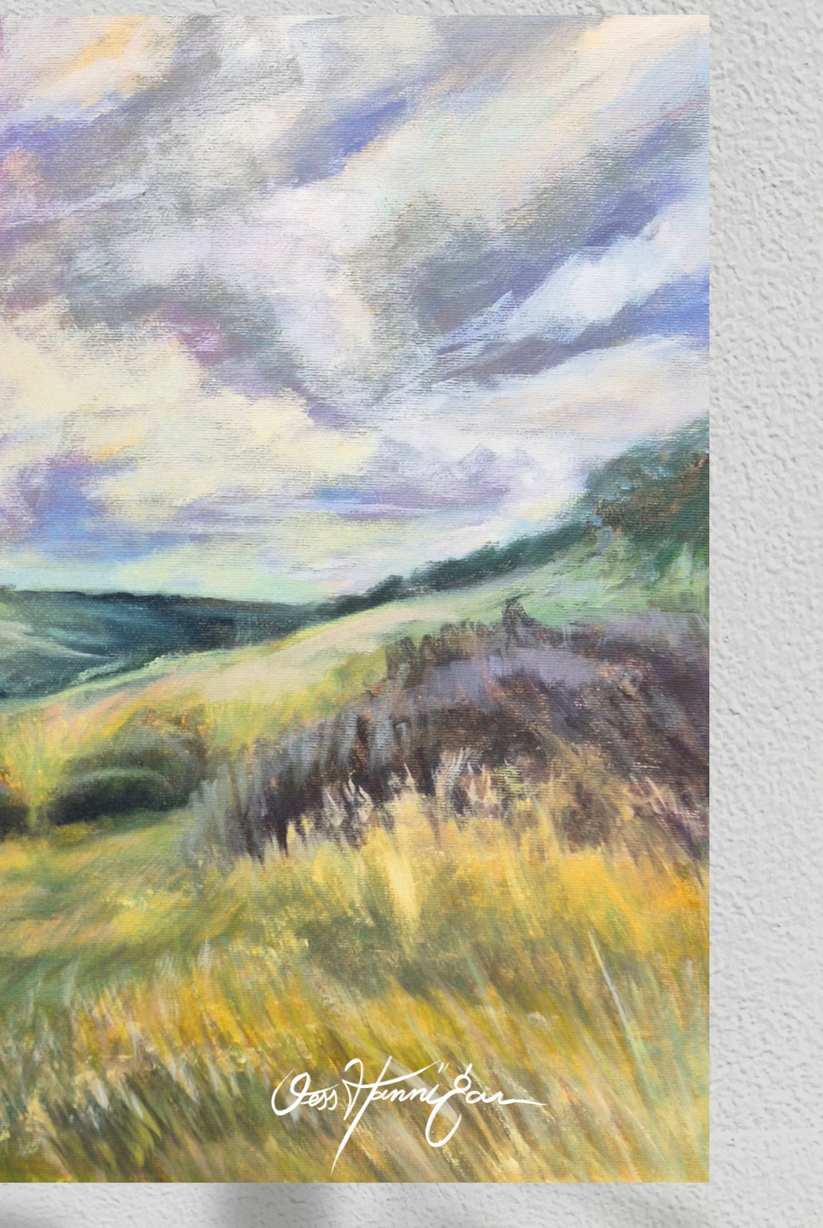 An impressionistic landscape painting of rolling green and yellow hills under a dramatic cloudy sky, displayed on a textured white wall. The artist's signature 'Gretchen Tomasi' is visible in white script at the bottom.