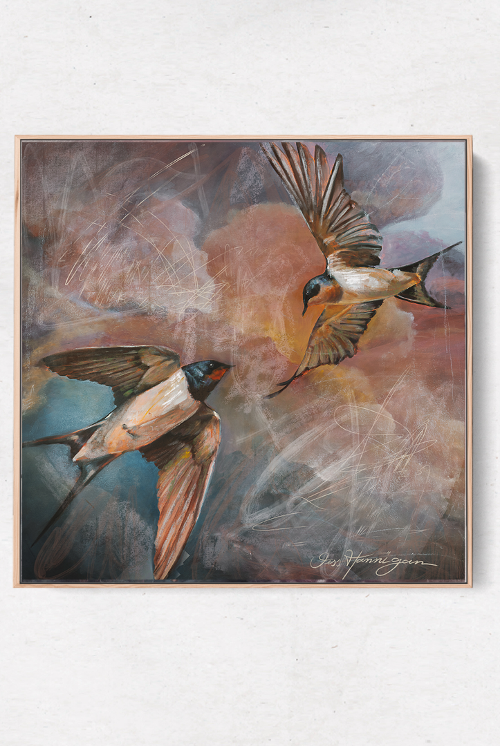 Framed artwork of two birds in flight on a white wall