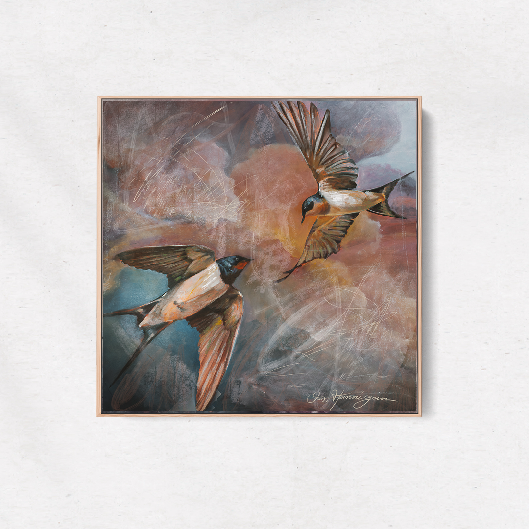 Framed artwork of two birds in flight on a white wall